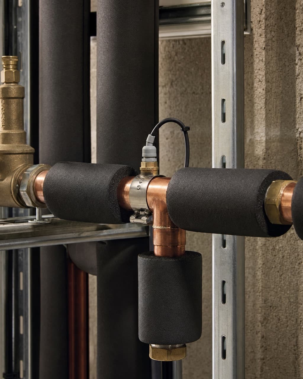 Insulated copper pipework in a service riser with a dead leg blanked off and a temperature sensor on the flow pipe